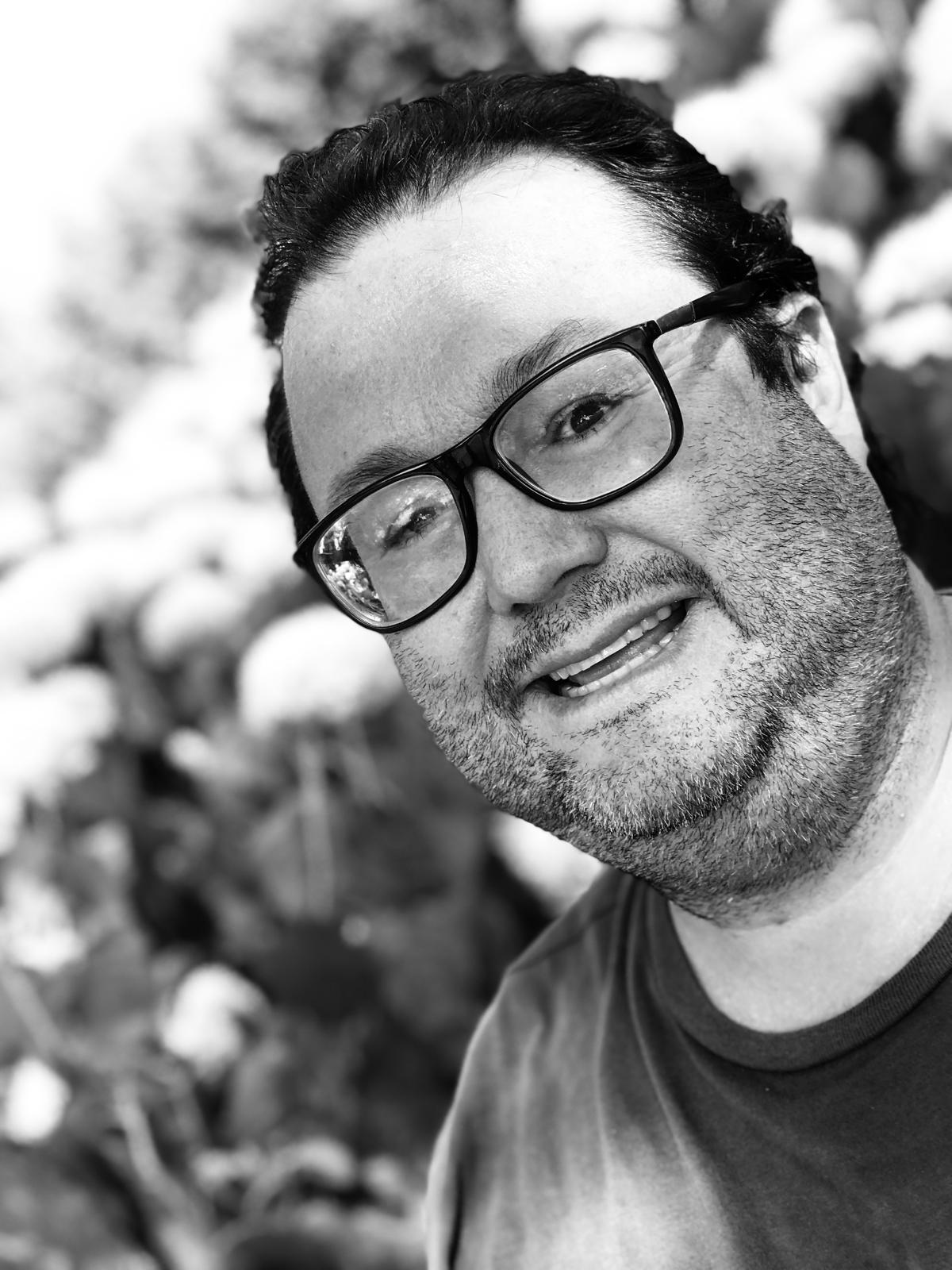 homem branco de meia idade, usando óculos, sorrindo