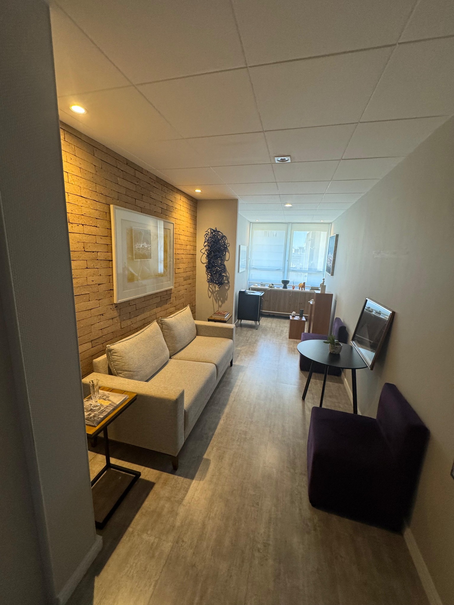 Sala de espera elegante, com sofás, poltronas confortáveis e obras de arte